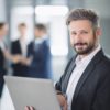 E-Mail richtig schreiben zeigt der Mitarbeiter auf dem Notebook